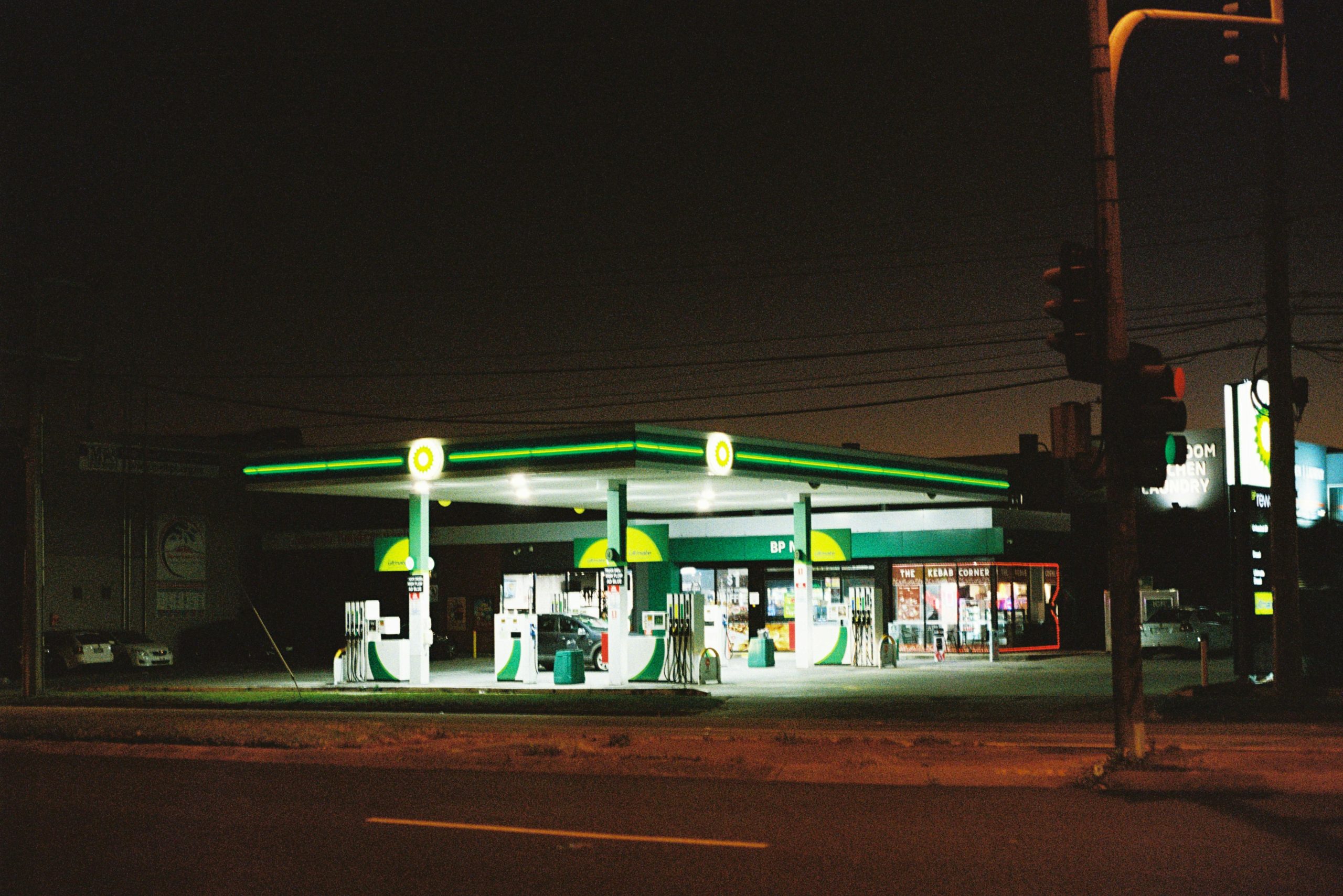 Illuminated BP gas station at night in Melbourne, showcasing urban life.